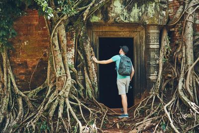 Full length of young man standing by tree