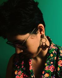 Close-up of young woman wearing eyeglasses against wall