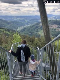 Rear view of people on railing against mountains