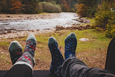 Man and woman feet in warm socks with mountain river on the background