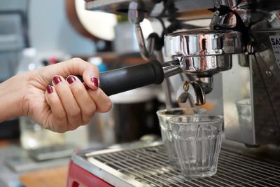 Cropped image of hand holding coffee cup at cafe