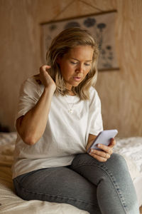 Woman in bedroom using cell phone