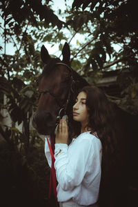 Rear view of young woman riding horse on field