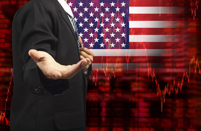 Midsection of businessman gesturing against american flag and chart