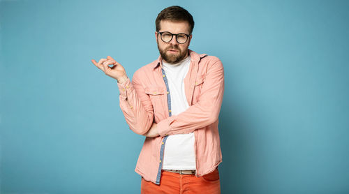 Young man standing against blue background
