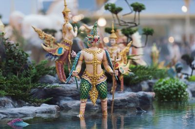 Tilt-shift image of statues by pond