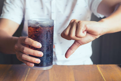 Midsection of man having beer while gesturing at table
