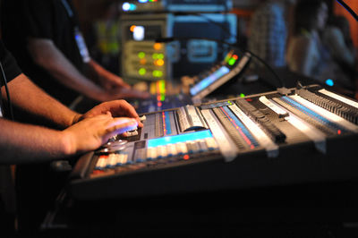 Midsection of men operating sound recording equipment in club