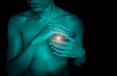 Midsection of shirtless man against black background
