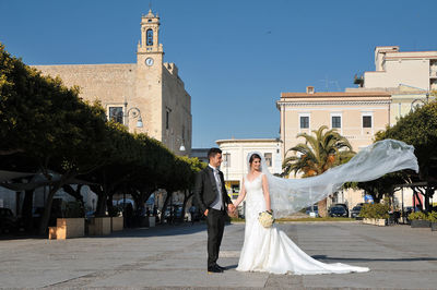 Wedding couple smiling while standing against buildings