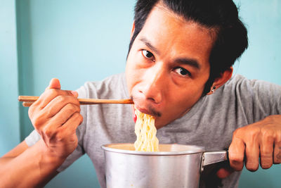 Portrait of man eating noodles at home