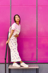 Portrait of young woman standing against wall