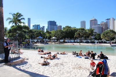 People at beach against clear blue sky