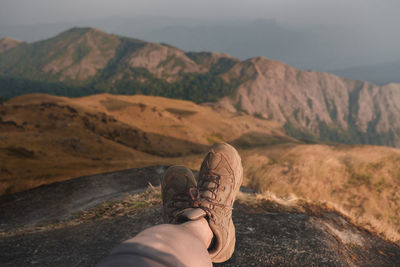 Midsection of person on rock against mountains