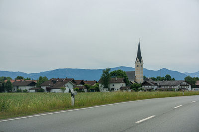 Road by buildings against sky in city