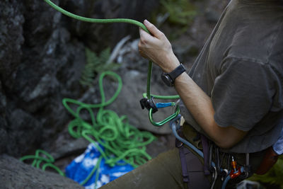 Mid section of rock climbers hands holding rope