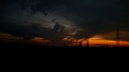 Silhouette of electricity pylon against dramatic sky