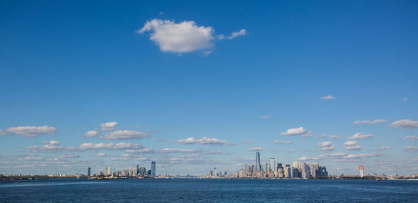 City at waterfront against cloudy sky