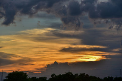 Low angle view of silhouette trees against dramatic sky