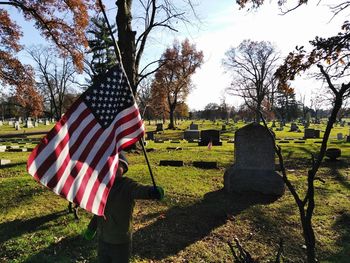 Rear view of boy in cemetery against sky