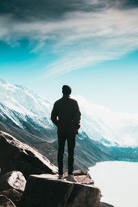 Rear view of man standing on mountain against sky