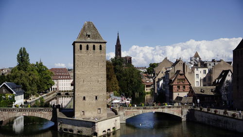 Arch bridge over river amidst buildings against sky