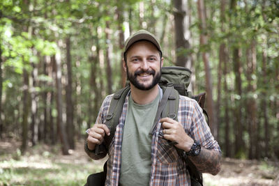 Portrait of smiling man with backpack on a hiking trip in forest