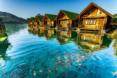 Houses by lake against blue sky