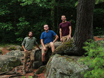 Young men on rock in forest