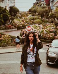 Portrait of young woman standing on street in city