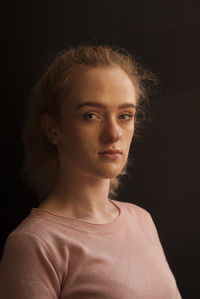 Close-up portrait of young woman against black background