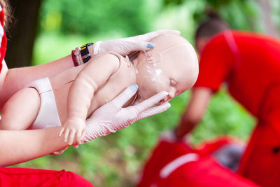 Close-up of female paramedic worker training on baby doll outdoors
