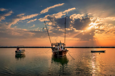 Sailboats in sea against sky during sunset