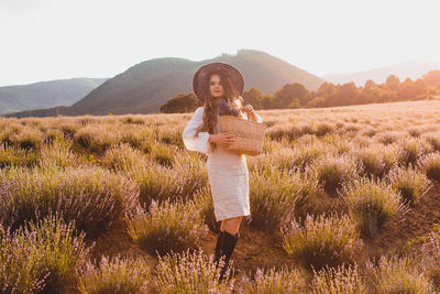 Full length of young woman standing on field against sky