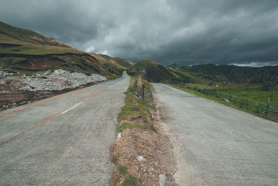 Road by mountain against storm clouds