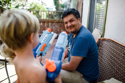 Nephews shooting water guns at uncle in front yard