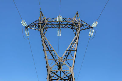 Low angle view of electricity pylon against clear blue sky