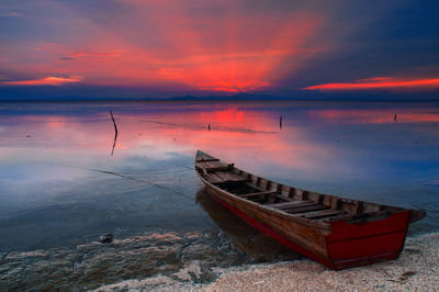 Boat moored on sea against sky during sunset