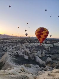 Hot air balloons flying over rocks against sky