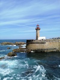 Lighthouse by sea against sky