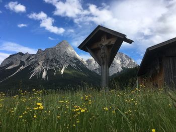 Scenic view of grassy field  and cross against cloudy sky and mountain sonnenspitze in tyrol