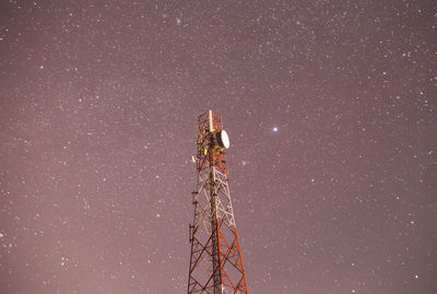 Low angle view of illuminated communications tower against sky at night