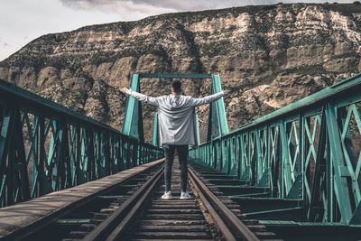 Man standing on bridge against sky