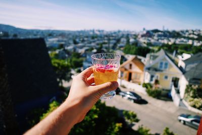 Close-up of hand holding drink against sky