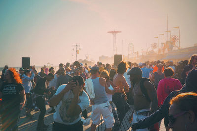 People dancing on floor at coney island against sky