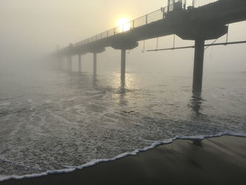 Pier over sea against sky during sunrise