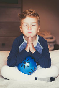 Portrait of cute boy sitting against blue wall