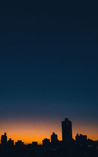 Silhouette buildings against clear sky at night