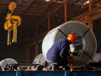 Worker is lashing steel coils onto trucks in warehouses to transport to the factory.