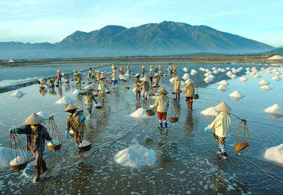 People working at salt lake against mountains